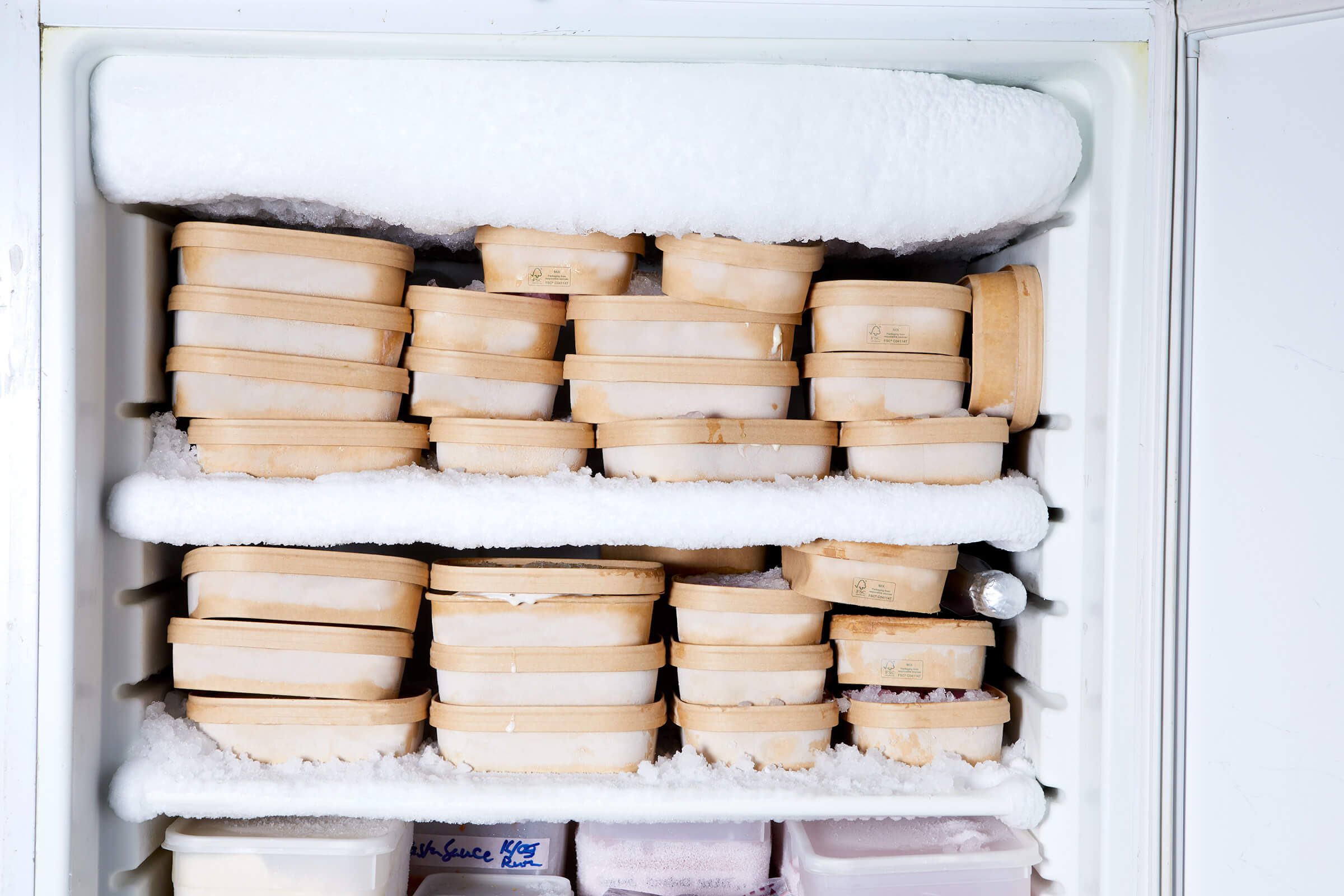 A frosted freezer stacked with kraft ice cream tubs